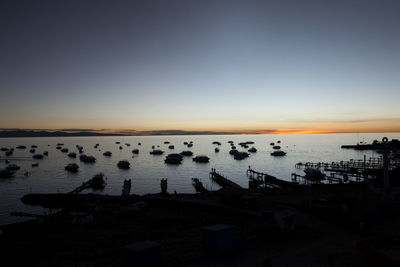 High angle view of silhouette people on sea against clear sky