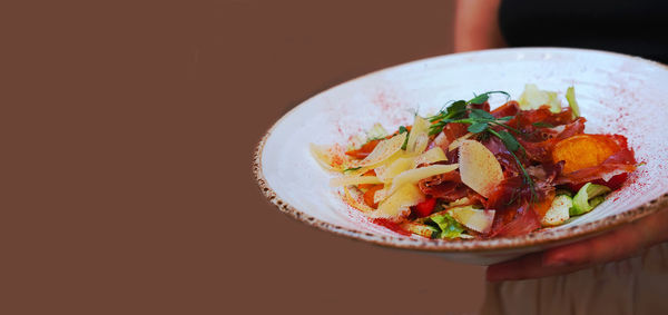 Delicate salad with ripe peach, cherry tomatoes, prosciutto, parmesan cheese and honey-mustard sauce