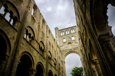 Low angle view of old building against cloudy sky