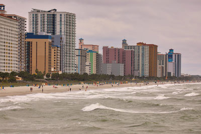 Modern buildings by sea against sky in city