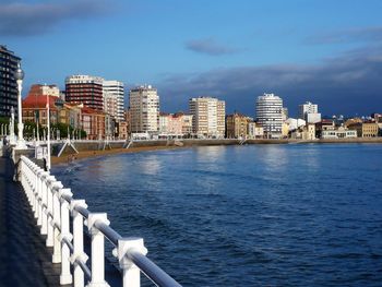 Sea by buildings against blue sky