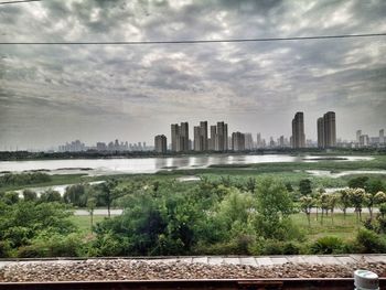 Cityscape by river against sky