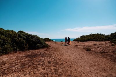 Family walking at beach against blue sky