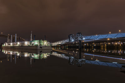 Illuminated bridge over river against sky at night