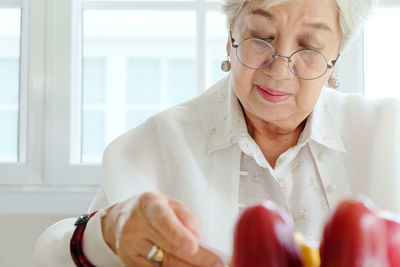 Fruits on table with senior woman reading book in background