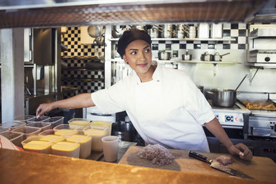 Female chef cooking while looking away at restaurant kitchen