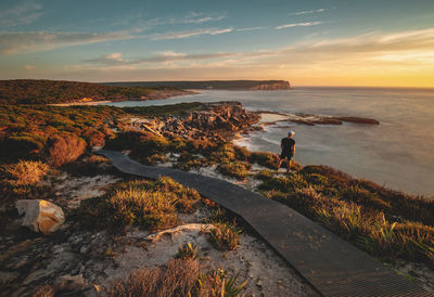 Full length of man standing on cliff during sunset