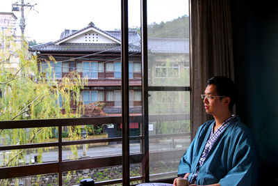 Young man looking through window in building