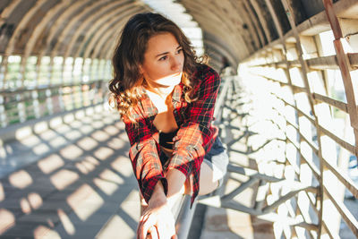 Thoughtful female dancer sitting on railing at pedestrian bridge