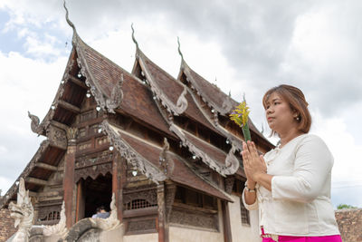 Woman praying while standing against temple