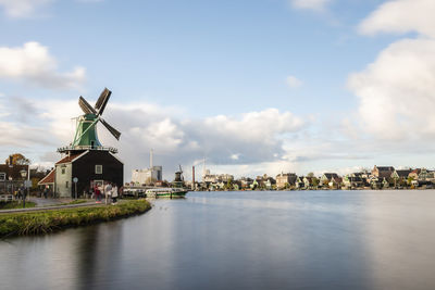 Traditional windmill by building against sky