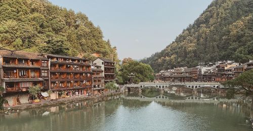 Buildings by river against sky