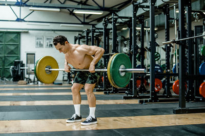 Muscular man lifting weights in health club