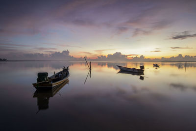 Boat moored in sea against sky during sunset