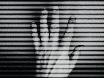 Shadow of person hand on window blinds