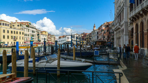 Boats moored in canal amidst buildings in city against sky