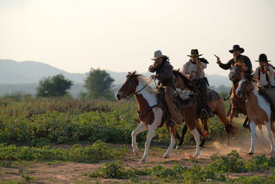 People riding horse on field against sky