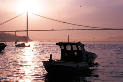 Boats in river at sunset