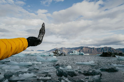 Male hand in yellow jacket holding black piece of ice in the glacier lagoon in iceland