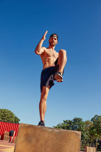 Low angle view of woman doing yoga against clear blue sky