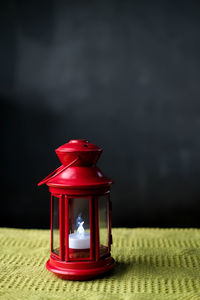 Close-up of illuminated lantern on table against wall