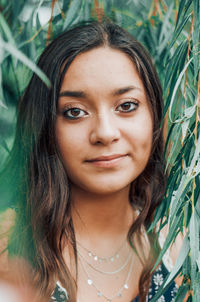 Close-up of a smiling young woman standing amidst plants outdoors