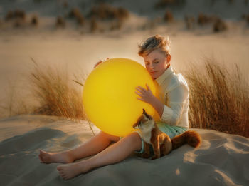 Young woman with cat on sand