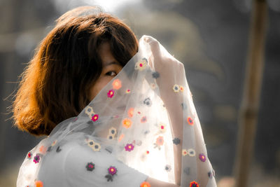 Portrait of woman holding dress standing outdoors