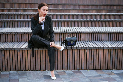 Business woman sitting on a bench in a suit and bag