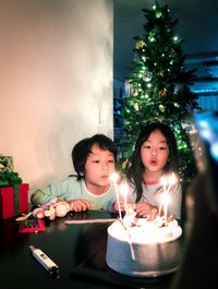 Siblings blowing candles on cake