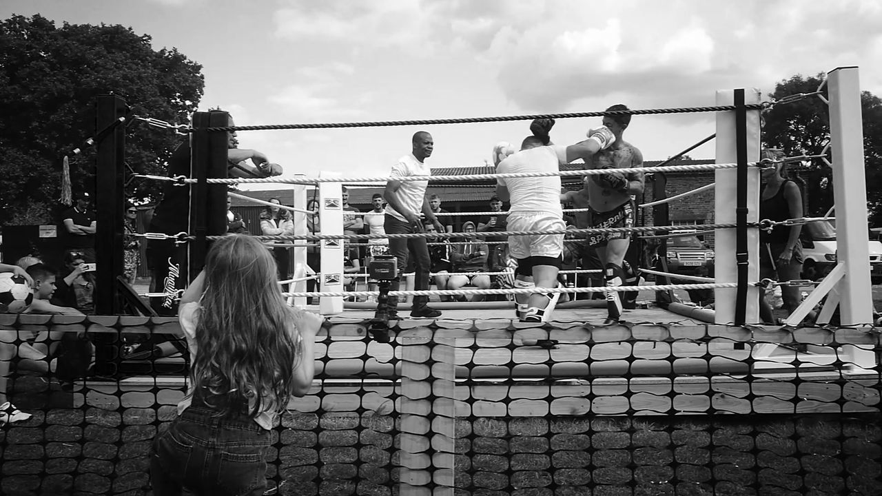 REAR VIEW OF TWO PEOPLE STANDING AGAINST RAILING