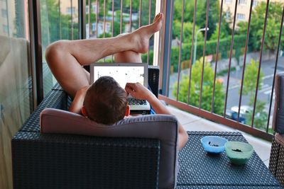 Man using laptop while lying on soda at home