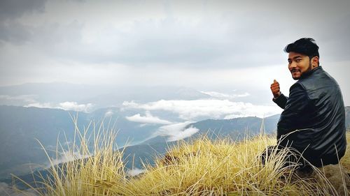 Young man standing on field against sky