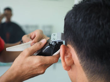 Cropped hand of barber cutting mid adult man hair