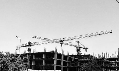 Low angle view of cranes against clear sky