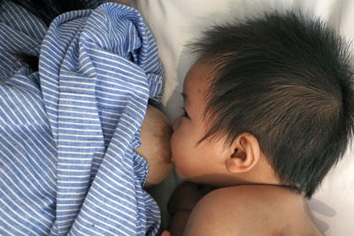 A close-up side view of a baby's face while nursing from his mother