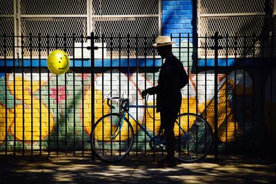 Man with bicycle standing on footpath against building