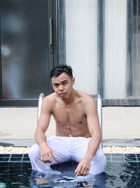 Portrait of young man sitting in swimming pool