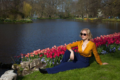 Young woman resting by tulips on lakeshore at park