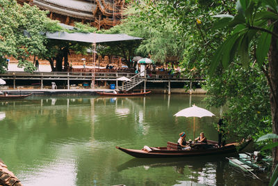 People sitting on boat in water against trees