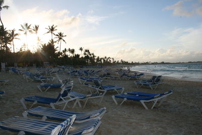 Chairs on beach against sky during sunset