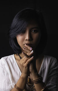 Close-up portrait of young woman against black background