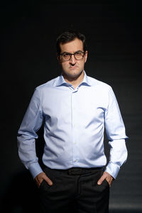 Young man standing against black background