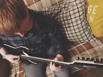 Midsection of man holding guitar at home