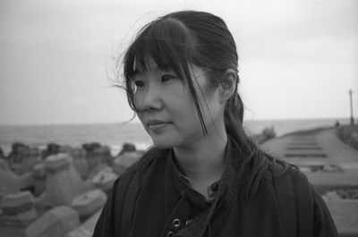 Portrait of young woman looking away against sea