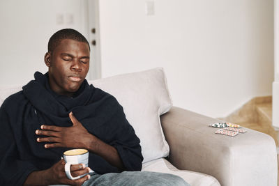 Midsection of man sitting on sofa at home