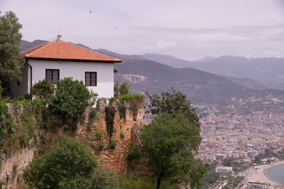 Houses and trees by mountains against sky