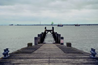 Pier on sea against cloudy sky