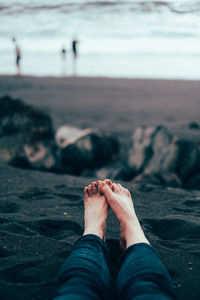 Low section of person sitting on sand at beach