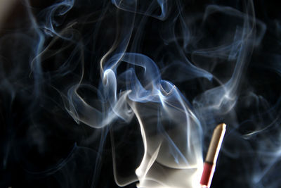 Close-up of burning incense against black background